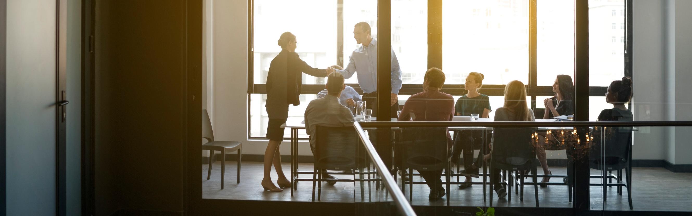 People in boardroom shaking hands