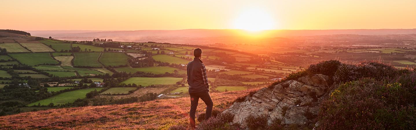 a man walking up a mountain at sunrise